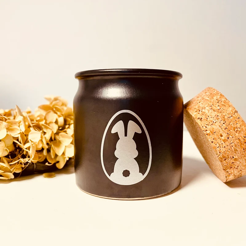 Handgemachte Duftkerze für Ostern in schwarzem Tontopf mit Korkdeckel
