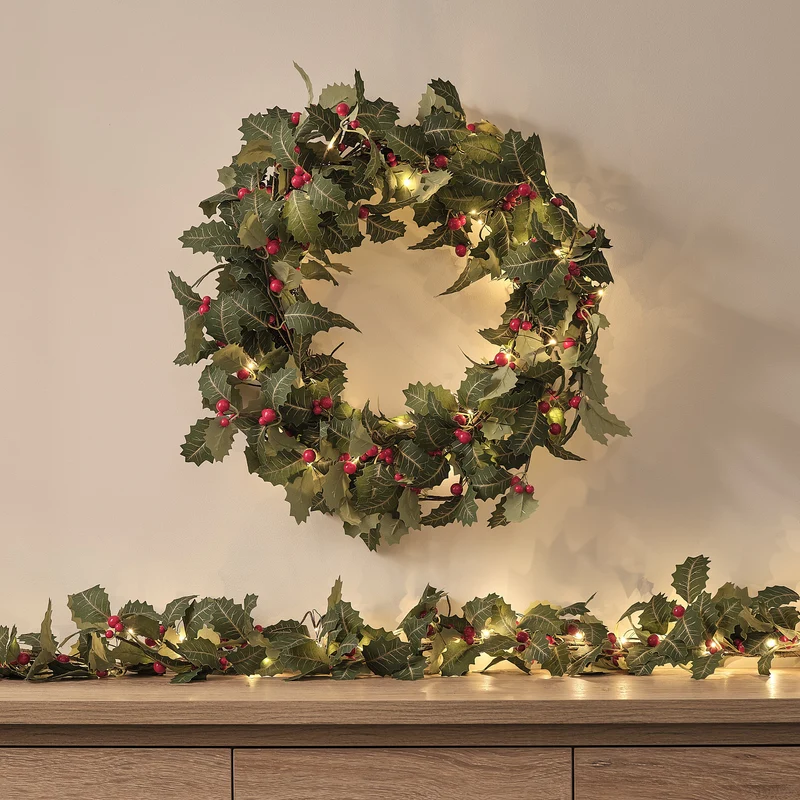 Weihnachtskranz und Weihnachtsgirlande mit Stechpalme und Beleuchtung