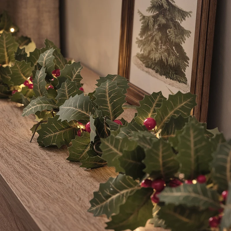 Weihnachtskranz und Weihnachtsgirlande mit Stechpalme und Beleuchtung