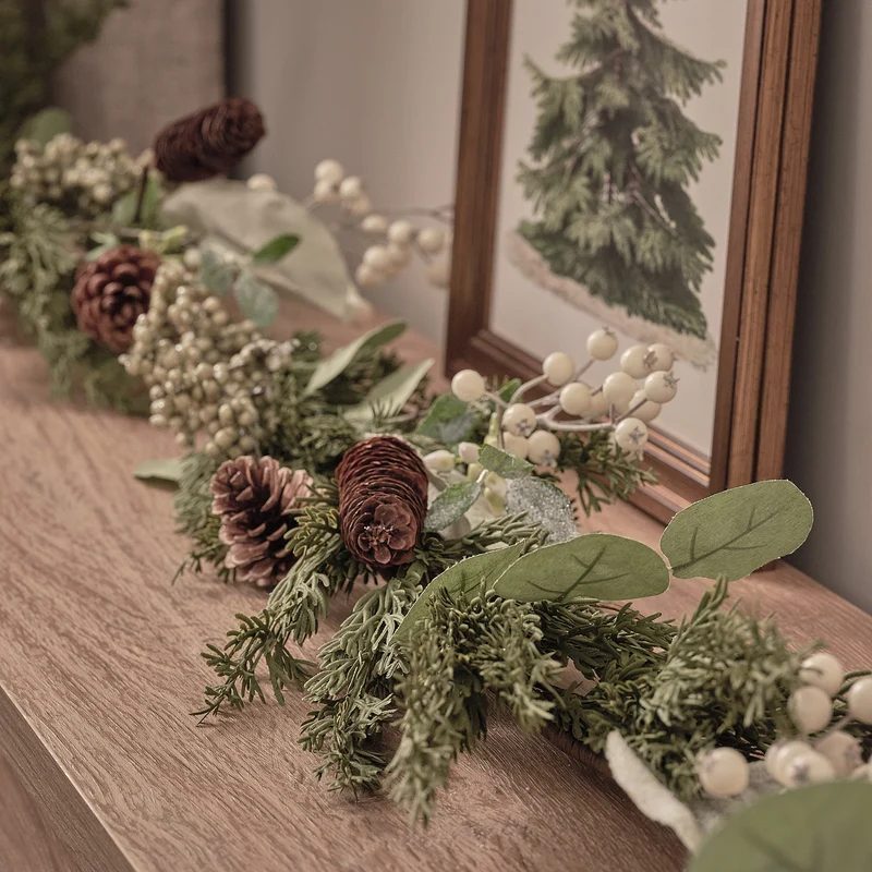 Weihnachtskranz und Girlande mit weißen Beeren und Tannenzapfen