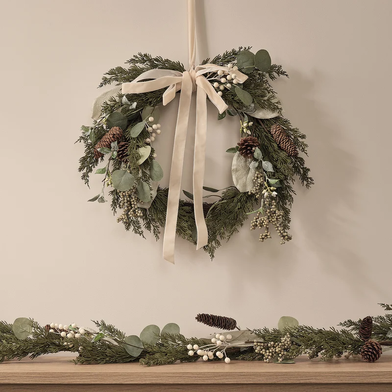Weihnachtskranz und Girlande mit weißen Beeren und Tannenzapfen