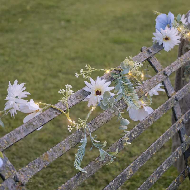 Beleuchteter Kranz und Girlande mit blauen und weißen Blüten