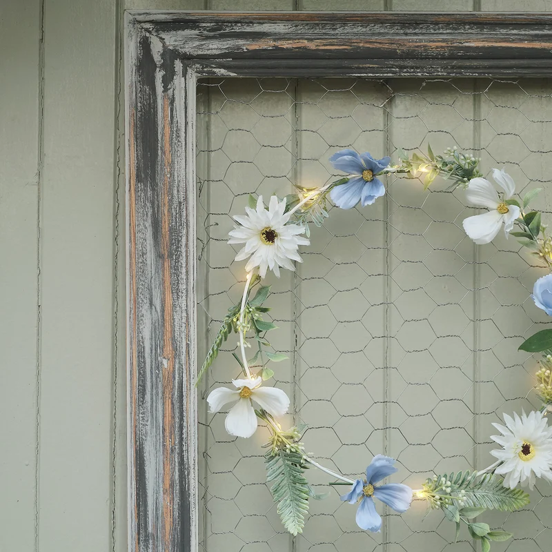 Beleuchteter Kranz und Girlande mit blauen und weißen Blüten