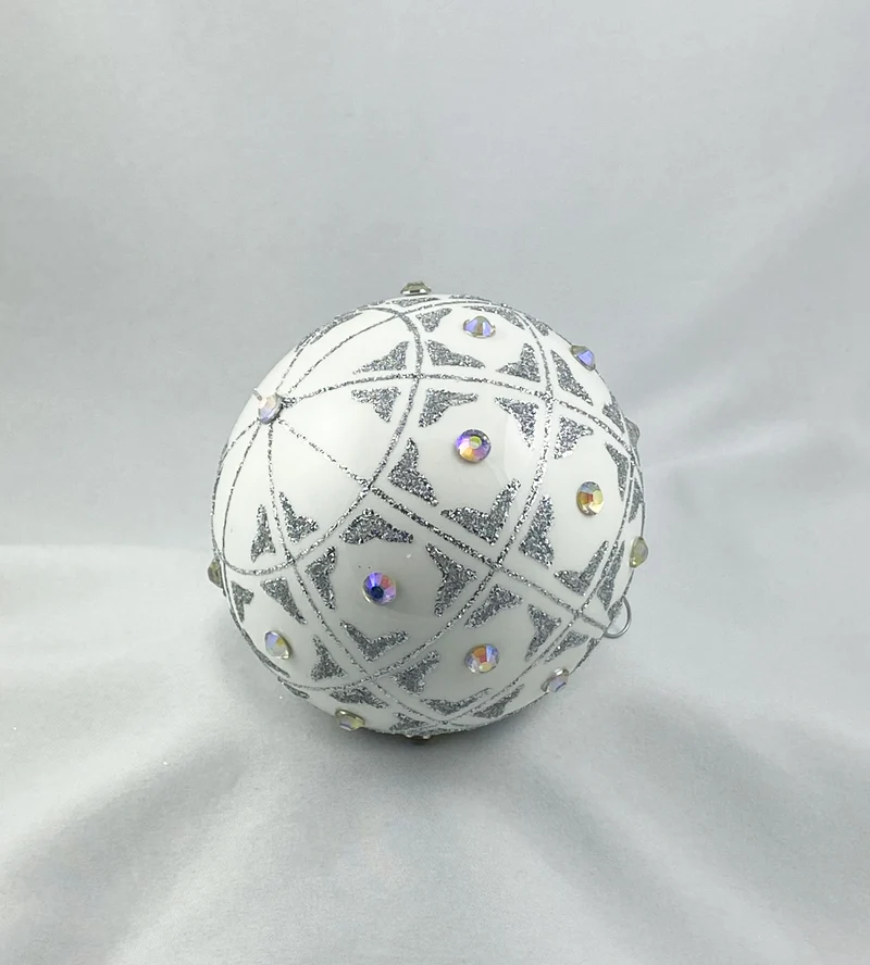 Kugel weiss mit geometrischem Muster und irisierenden Schmucksteinen