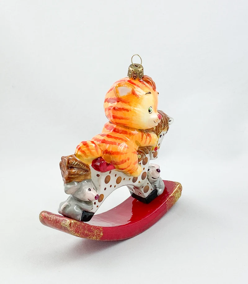 Die rote Tiger-Katze reitet auf dem getupften Schaukel-Pferdchen AtlasArt