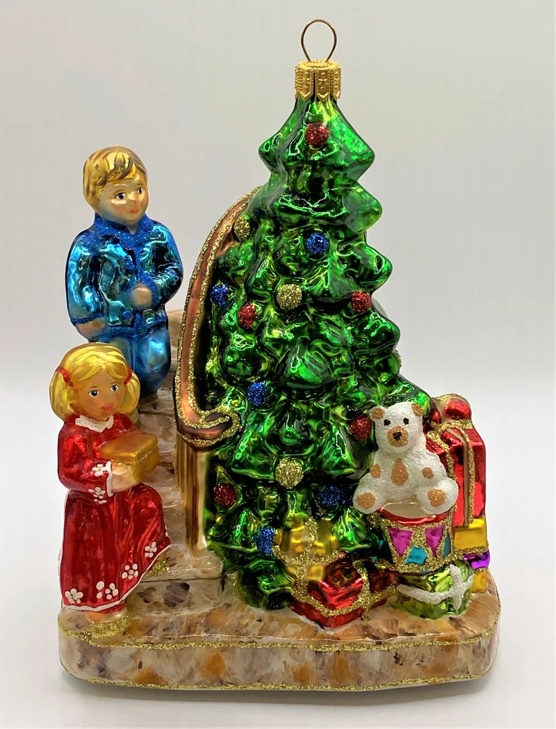 Die Kinder legen die Geschenke unter den Christbaum