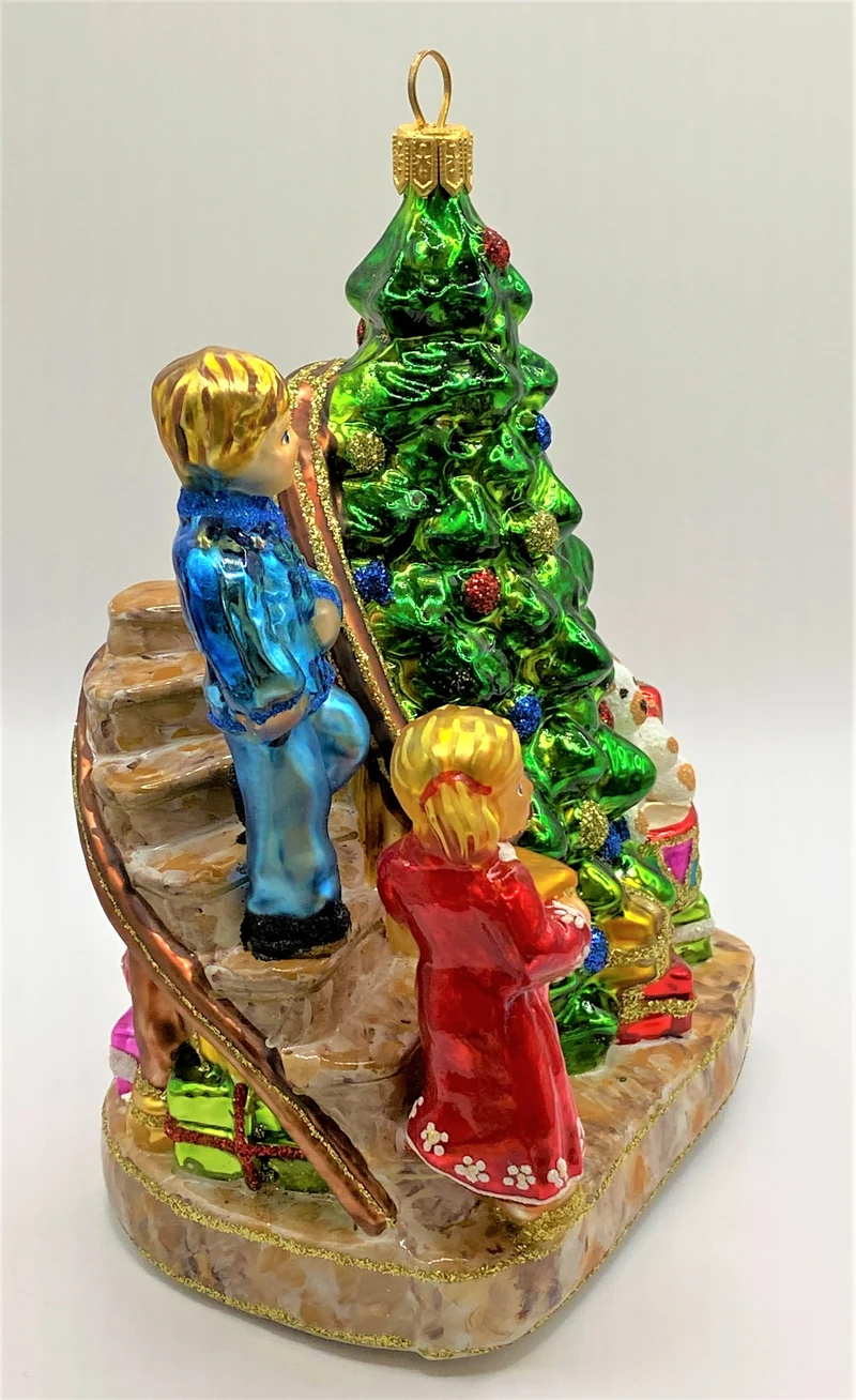 Die Kinder legen die Geschenke unter den Christbaum