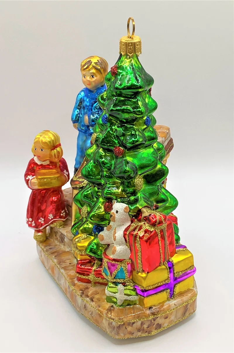 Die Kinder legen die Geschenke unter den Christbaum