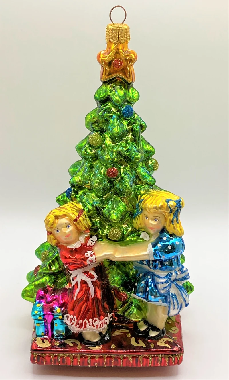 Zwei Mädchen tanzen um den Christbaum