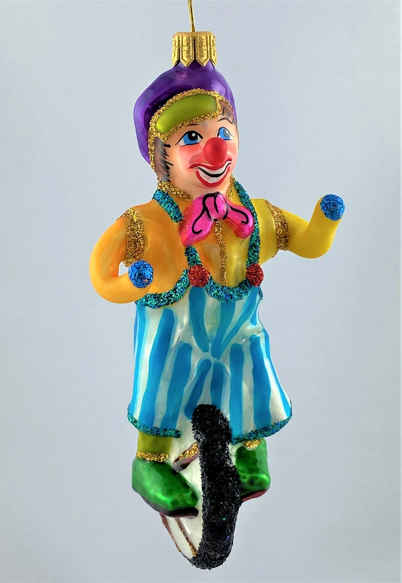 Clown in gestreifter Hose fährt Einrad