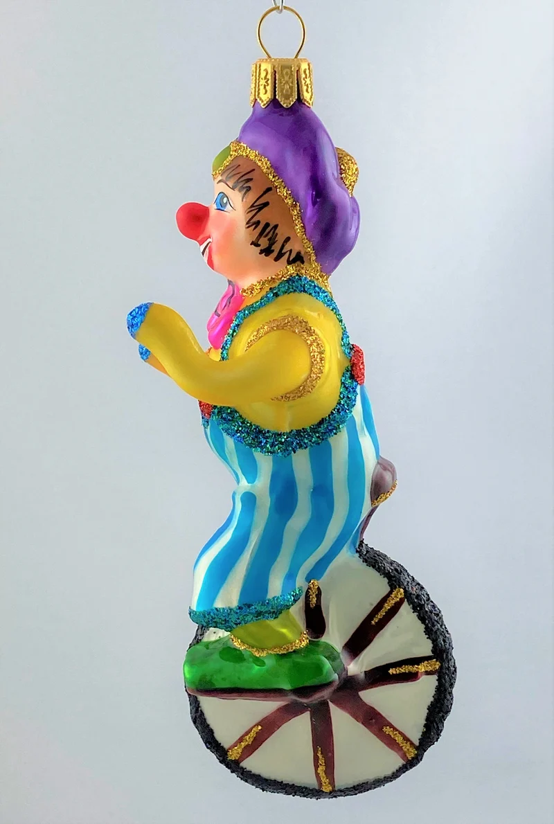 Clown in gestreifter Hose fährt Einrad