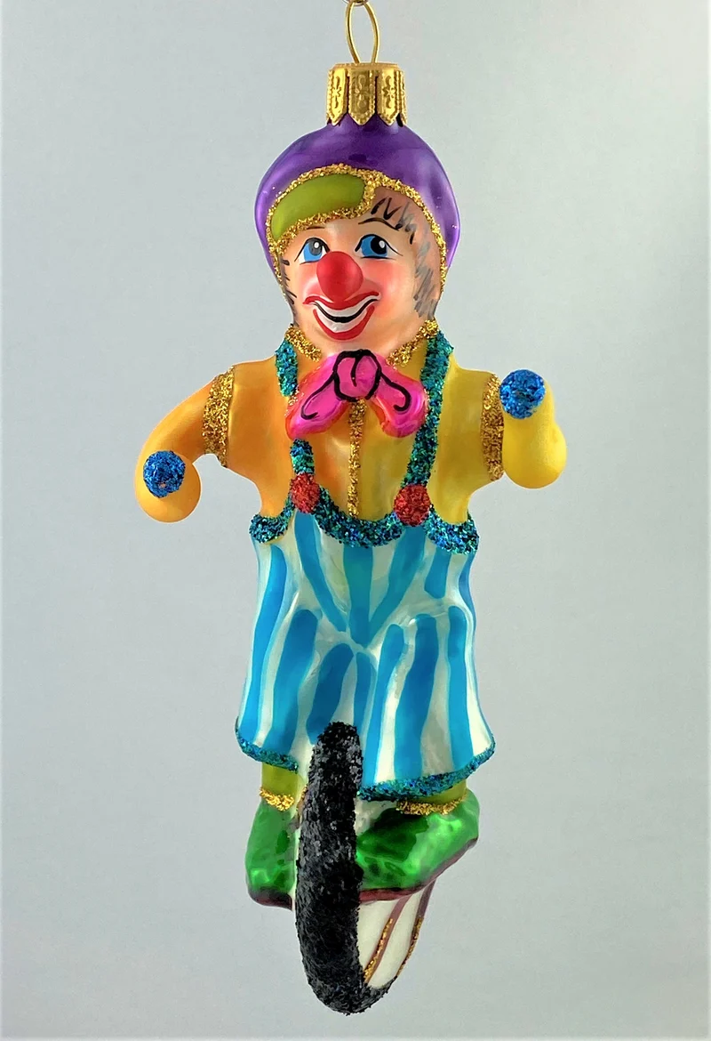 Clown in gestreifter Hose fährt Einrad