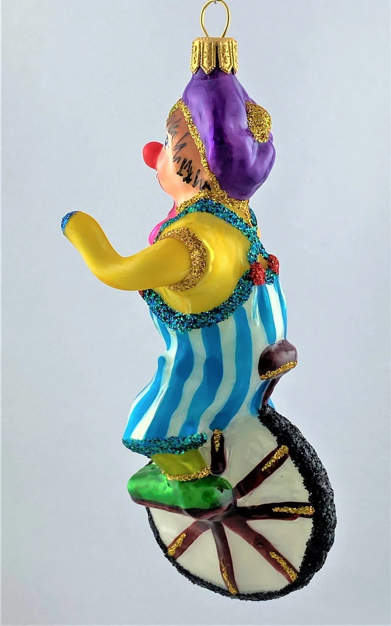 Clown in gestreifter Hose fährt Einrad