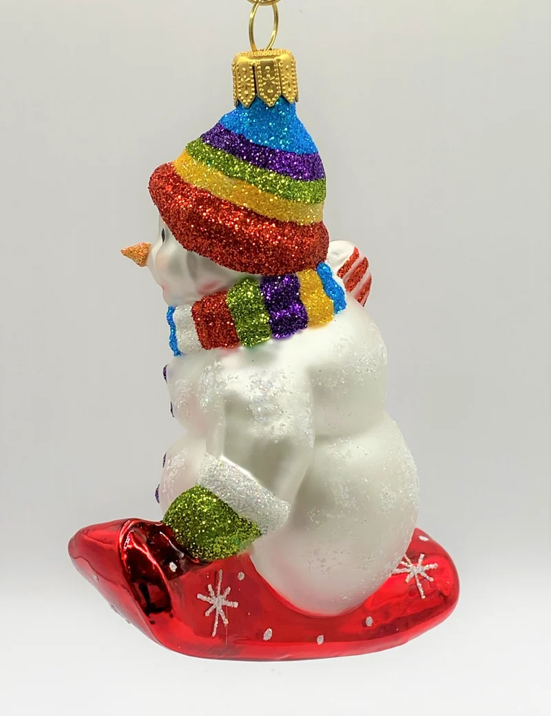 Schneemann mit bunter Mütze auf Snowboard