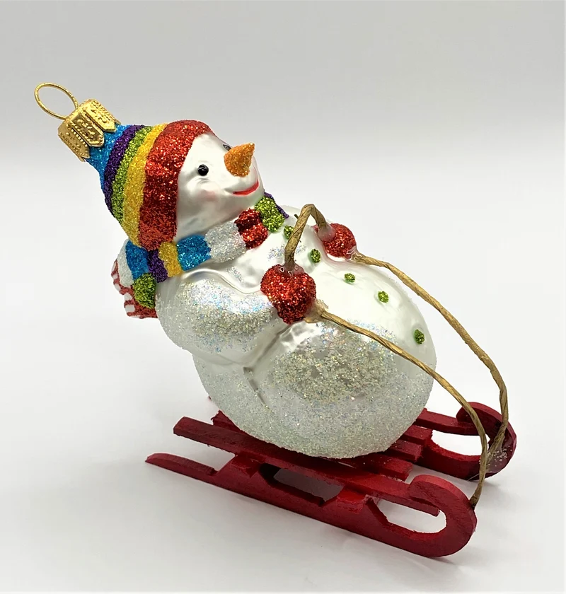 Schneemann mit bunter Mütze auf Schlitten