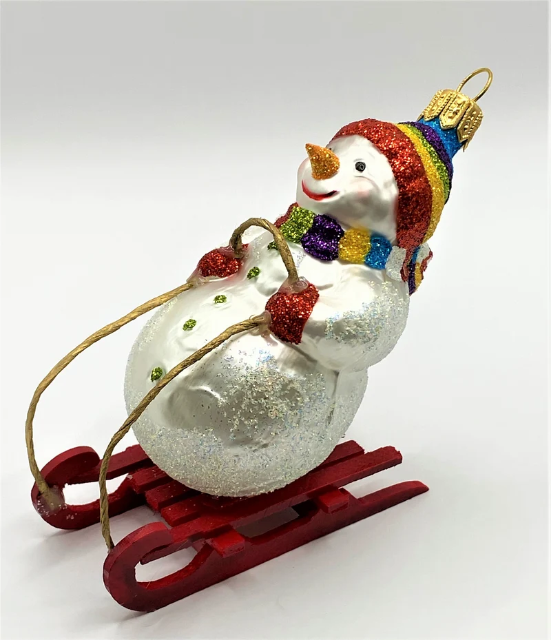Schneemann mit bunter Mütze auf Schlitten