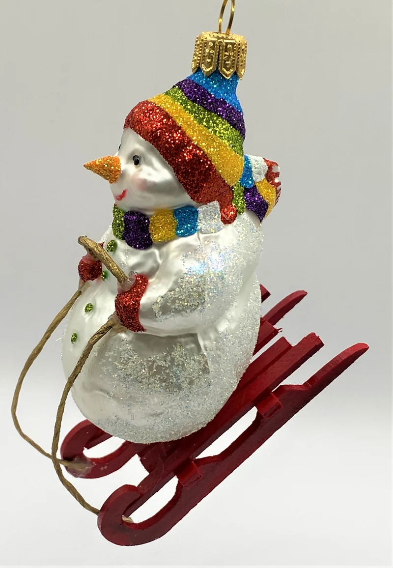 Schneemann mit bunter Mütze auf Schlitten