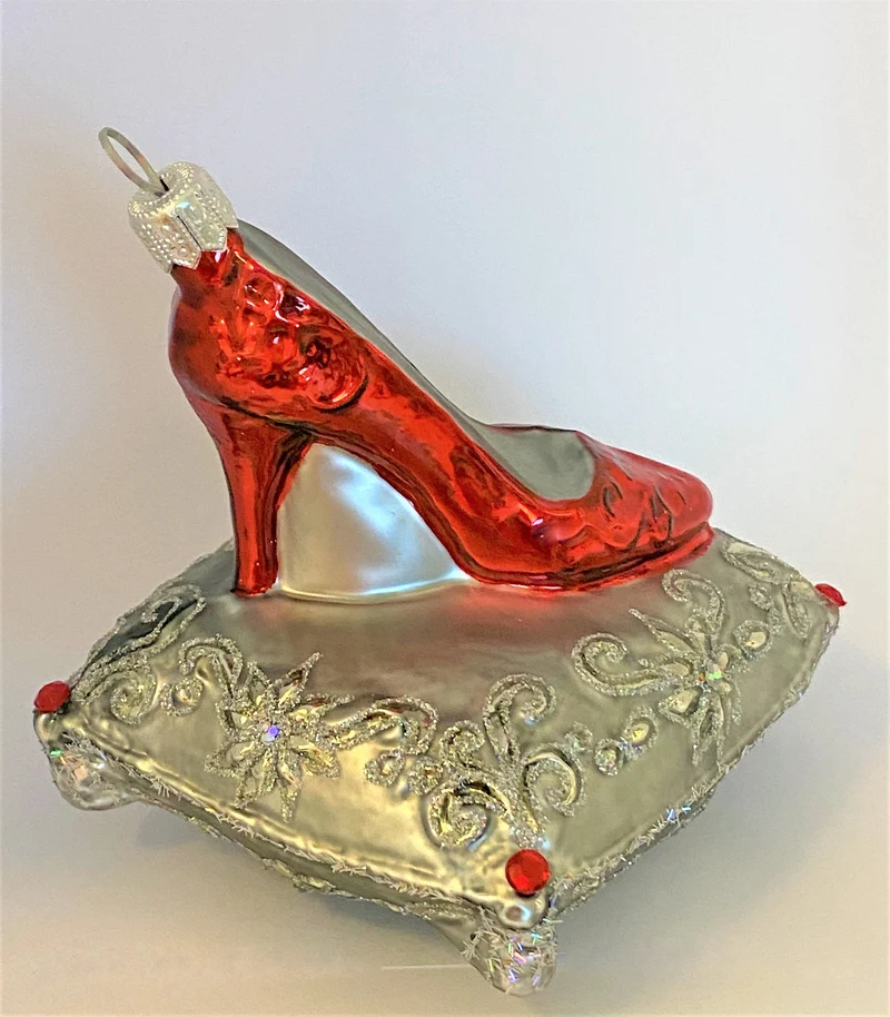 Roter High Heels auf silbernem Brokatkissen