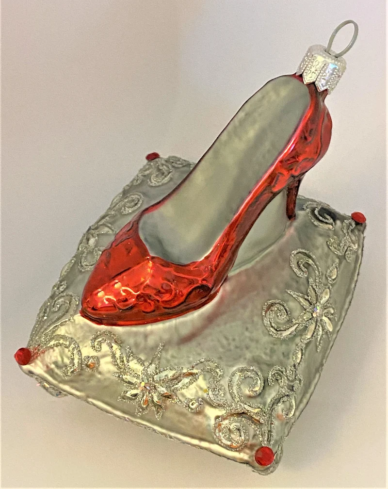 Roter High Heels auf silbernem Brokatkissen