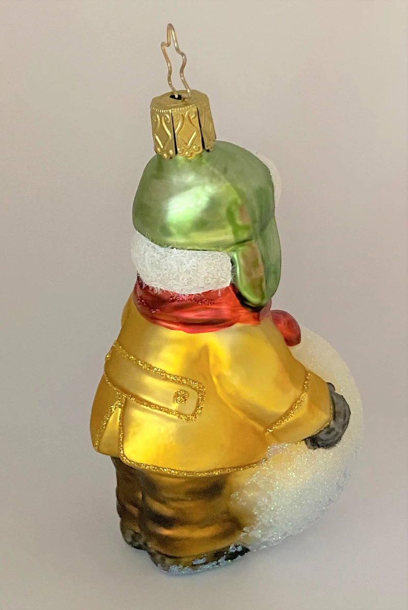 Kleiner Junge mit grüner Wintermütze macht einen riesigen Schneeball