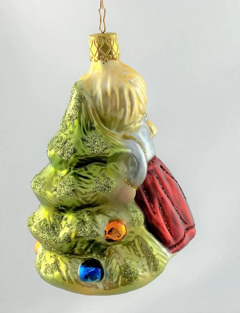 Das kleinen Mädchen umarmt den Christbaum