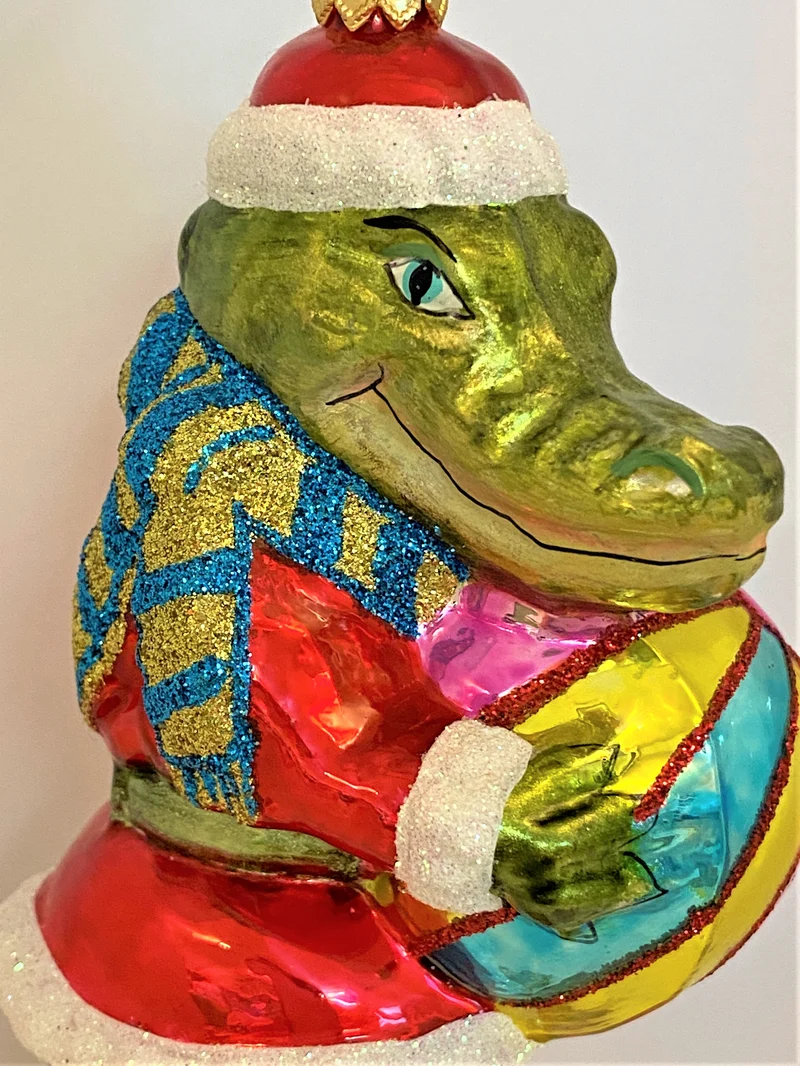 Krokodil im Santa-Kostüm spielt mit dem Ball