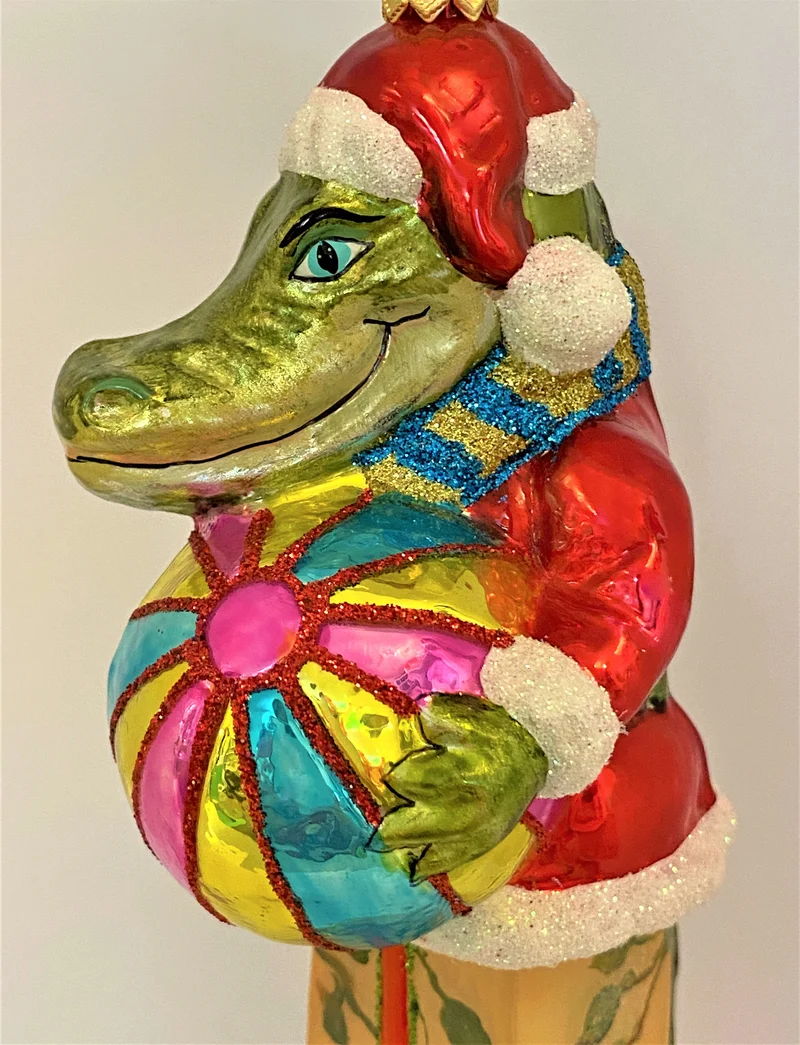 Krokodil im Santa-Kostüm spielt mit dem Ball