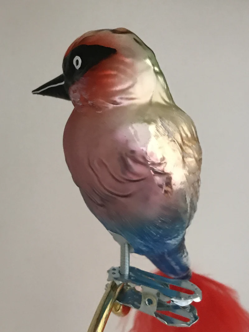 Bunter Vogel auf Clip mit roter Naturfeder