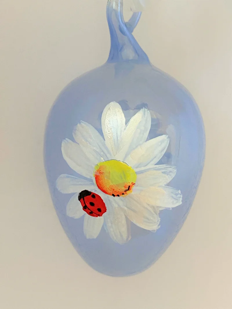 Hellblaues Osterei mit Gänseblümchen