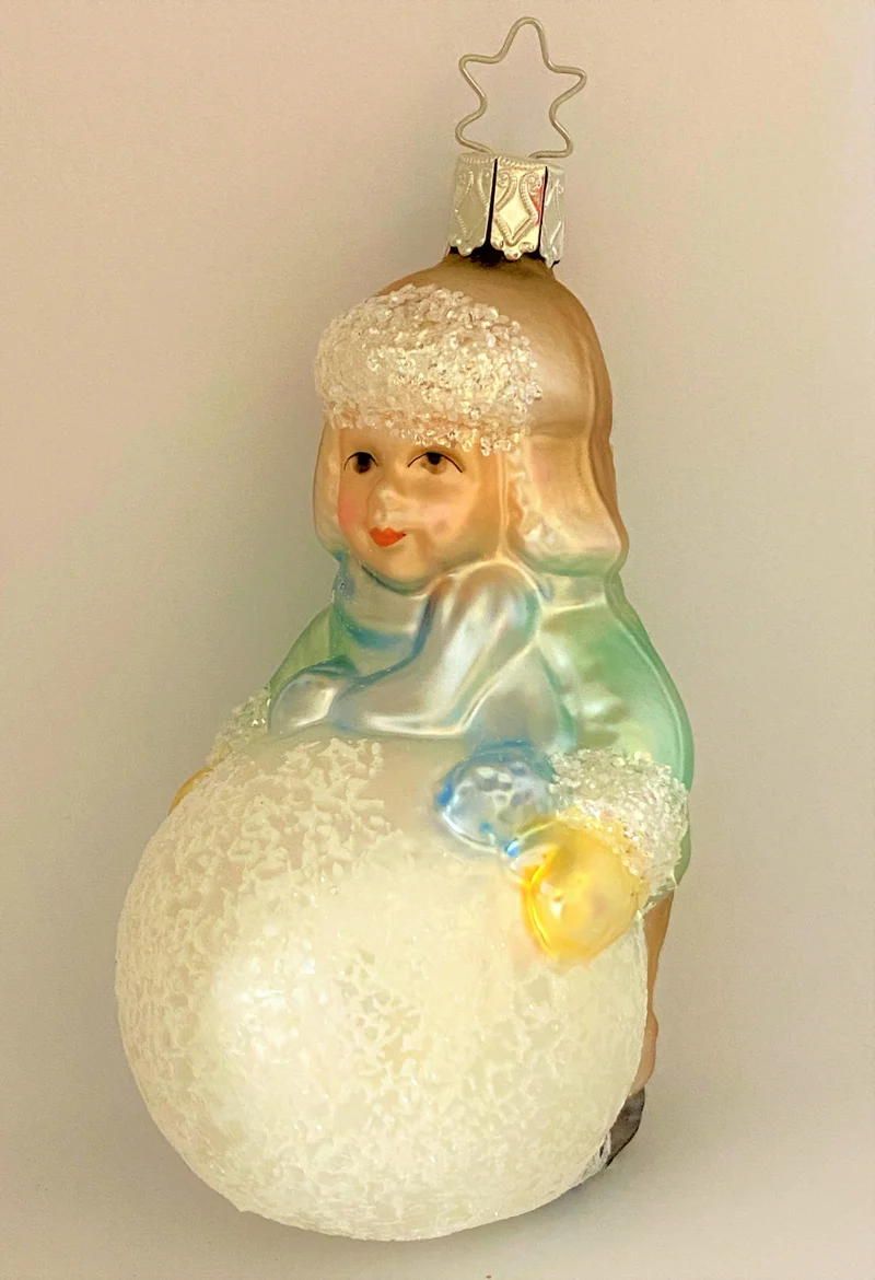 Kleiner Junge mit Wintermütze macht einen riesigen Schneeball, pastell