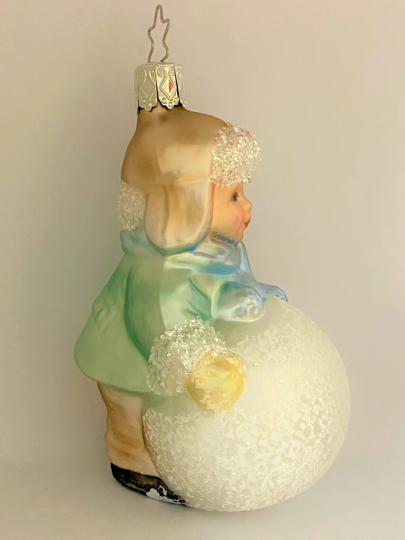 Kleiner Junge mit Wintermütze macht einen riesigen Schneeball, pastell