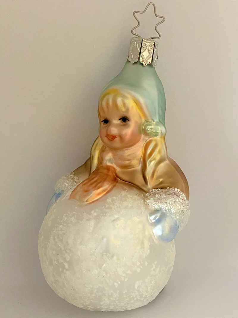 Kleines Mädchen mit Wintermütze macht einen riesigen Schneeball, pastell