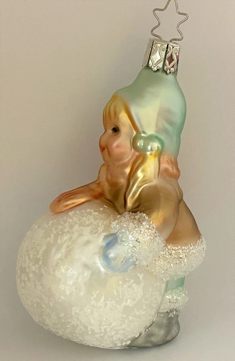 Kleines Mädchen mit Wintermütze macht einen riesigen Schneeball, pastell