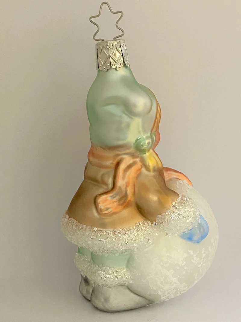 Kleines Mädchen mit Wintermütze macht einen riesigen Schneeball, pastell