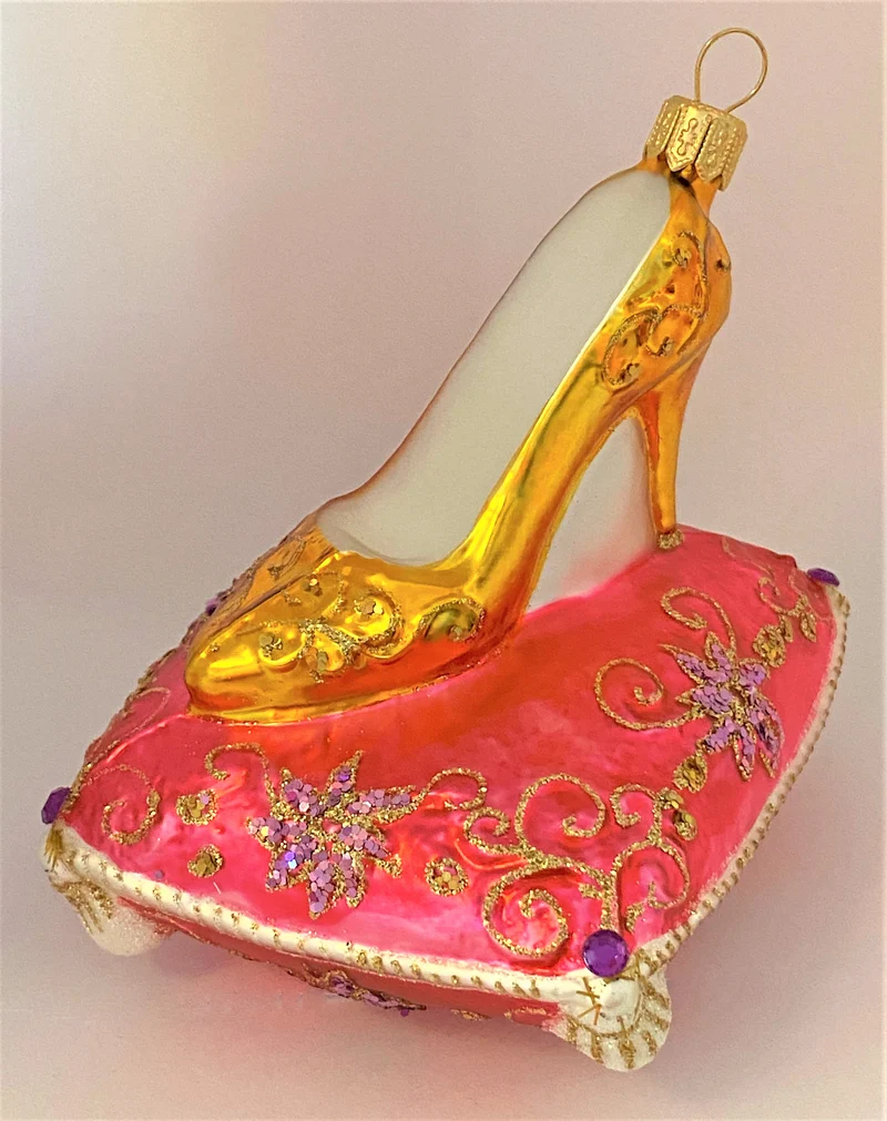Goldener High Heel auf rosa Brokatkissen