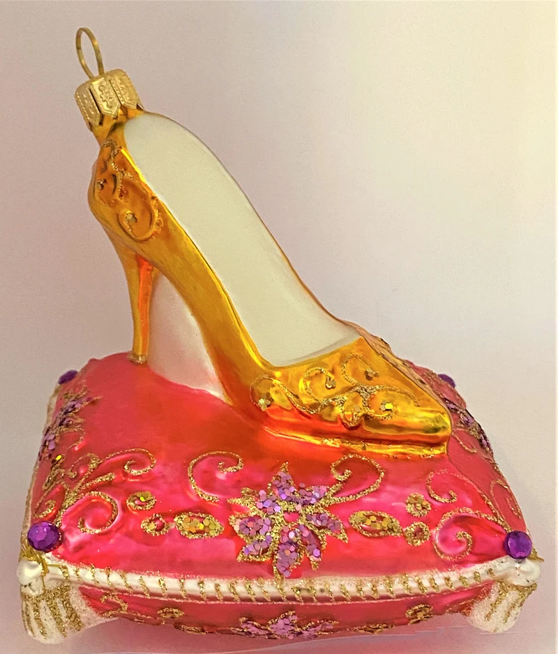 Goldener High Heel auf rosa Brokatkissen