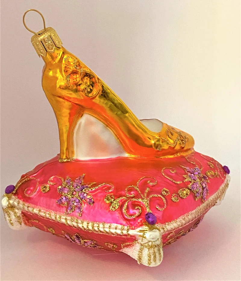 Goldener High Heel auf rosa Brokatkissen