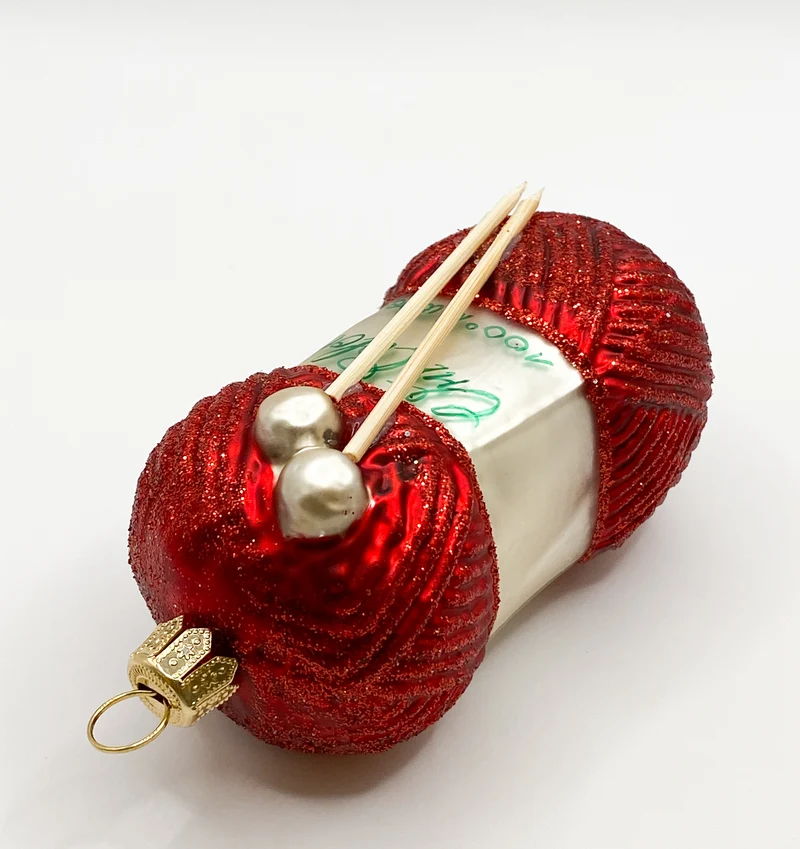 Roter Wollknäuel mit Stricknadeln