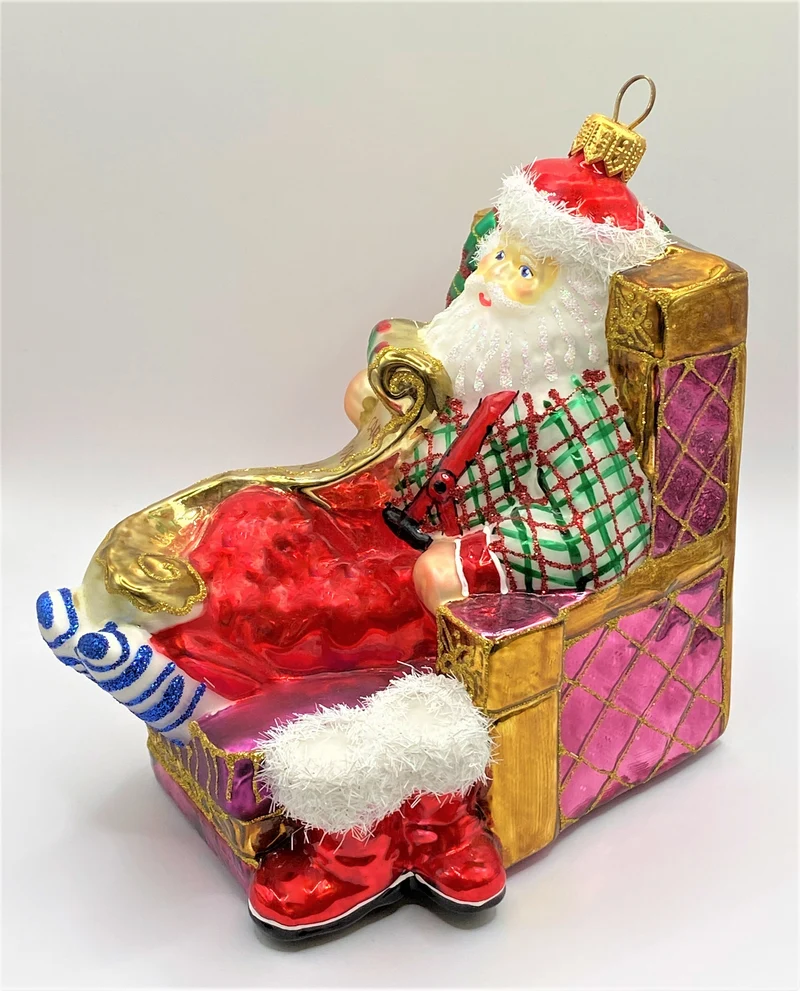 Santa Claus sitzt bequem im Sessel und studiert die Geschenke-Liste