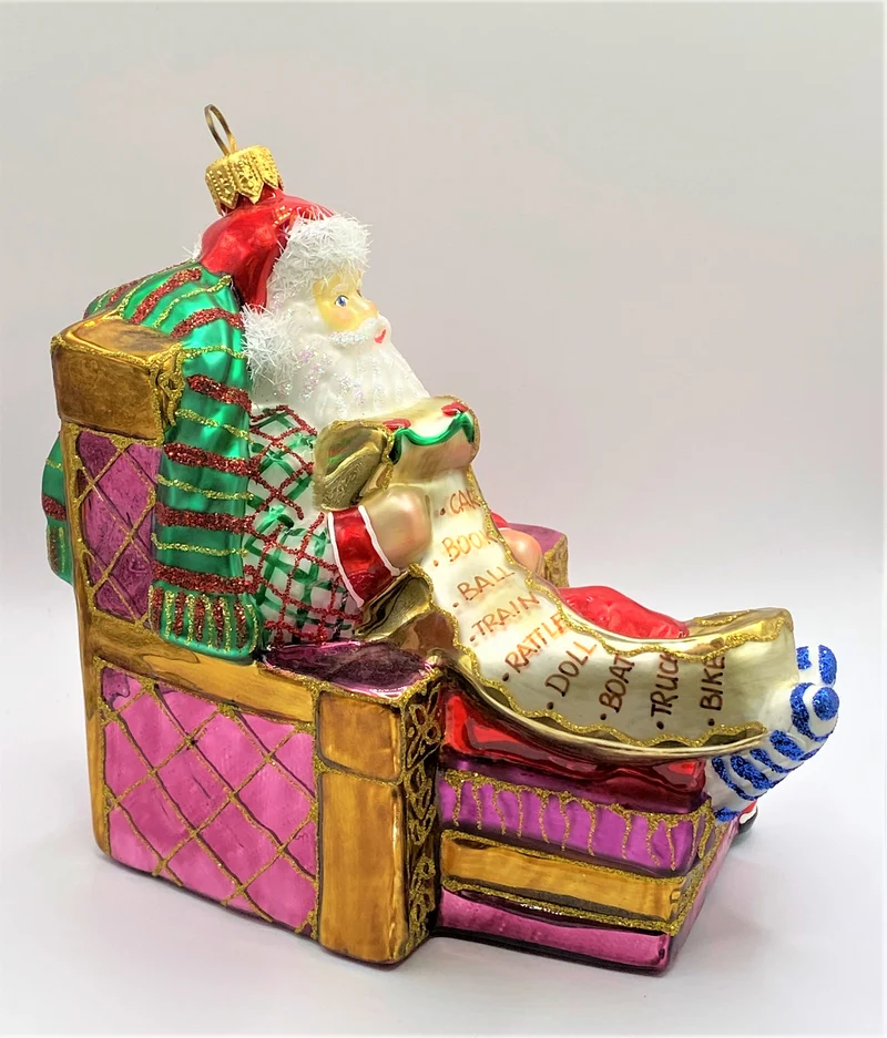 Santa Claus sitzt bequem im Sessel und studiert die Geschenke-Liste