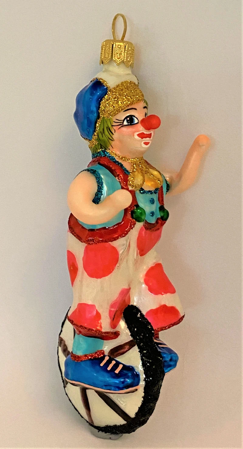Clown mit weiss-rot getupften Hosen fährt Einrad