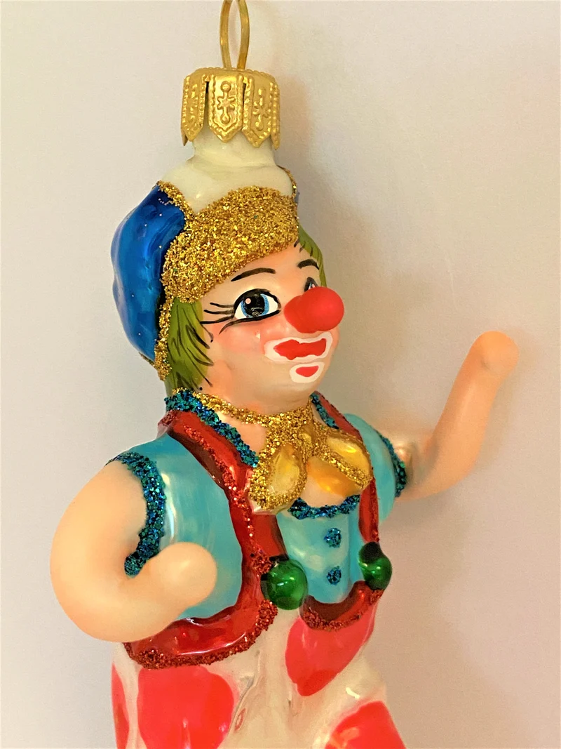 Clown mit weiss-rot getupften Hosen fährt Einrad