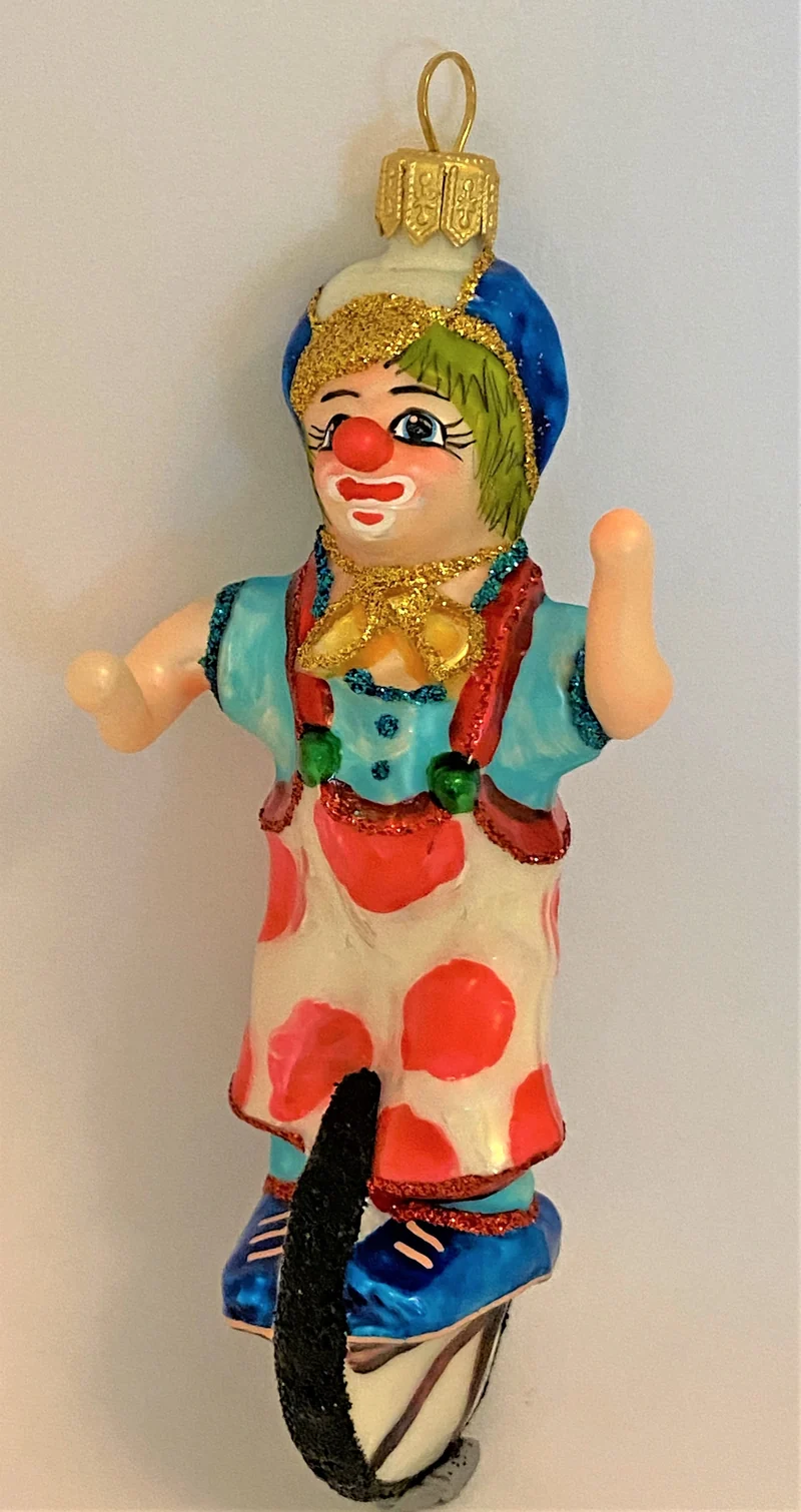 Clown mit weiss-rot getupften Hosen fährt Einrad