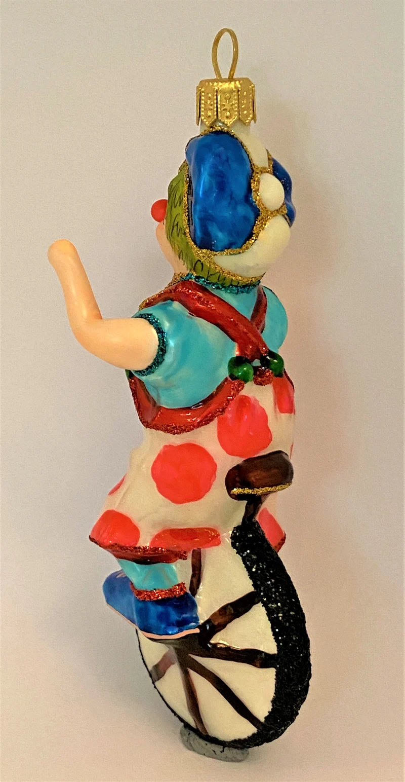 Clown mit weiss-rot getupften Hosen fährt Einrad