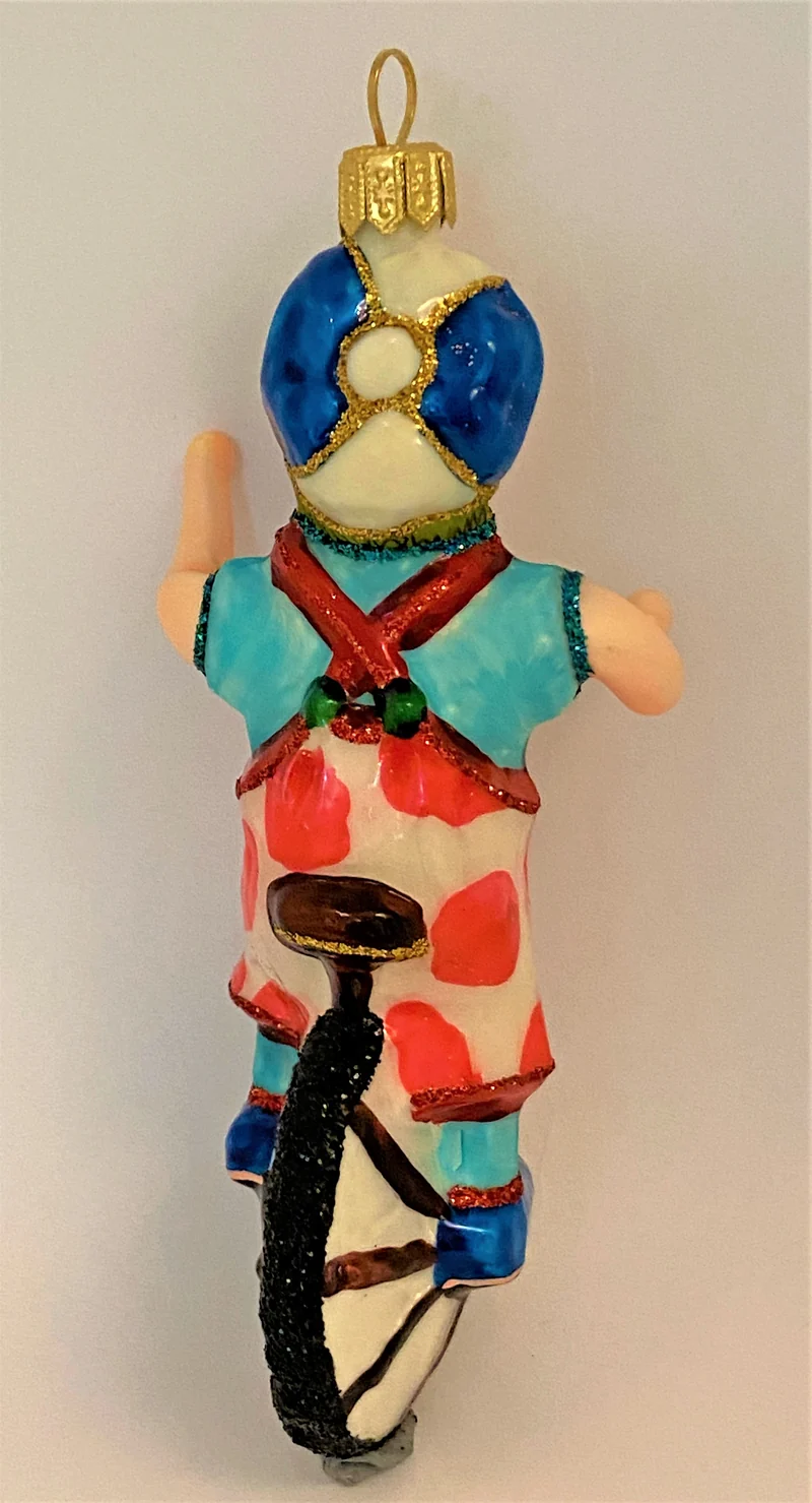 Clown mit weiss-rot getupften Hosen fährt Einrad