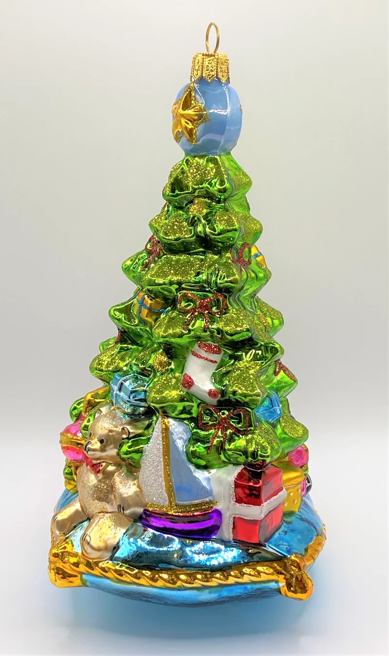 Christbaum mit Teddybär, Lokomotive und Segelboot auf blauem Kissen