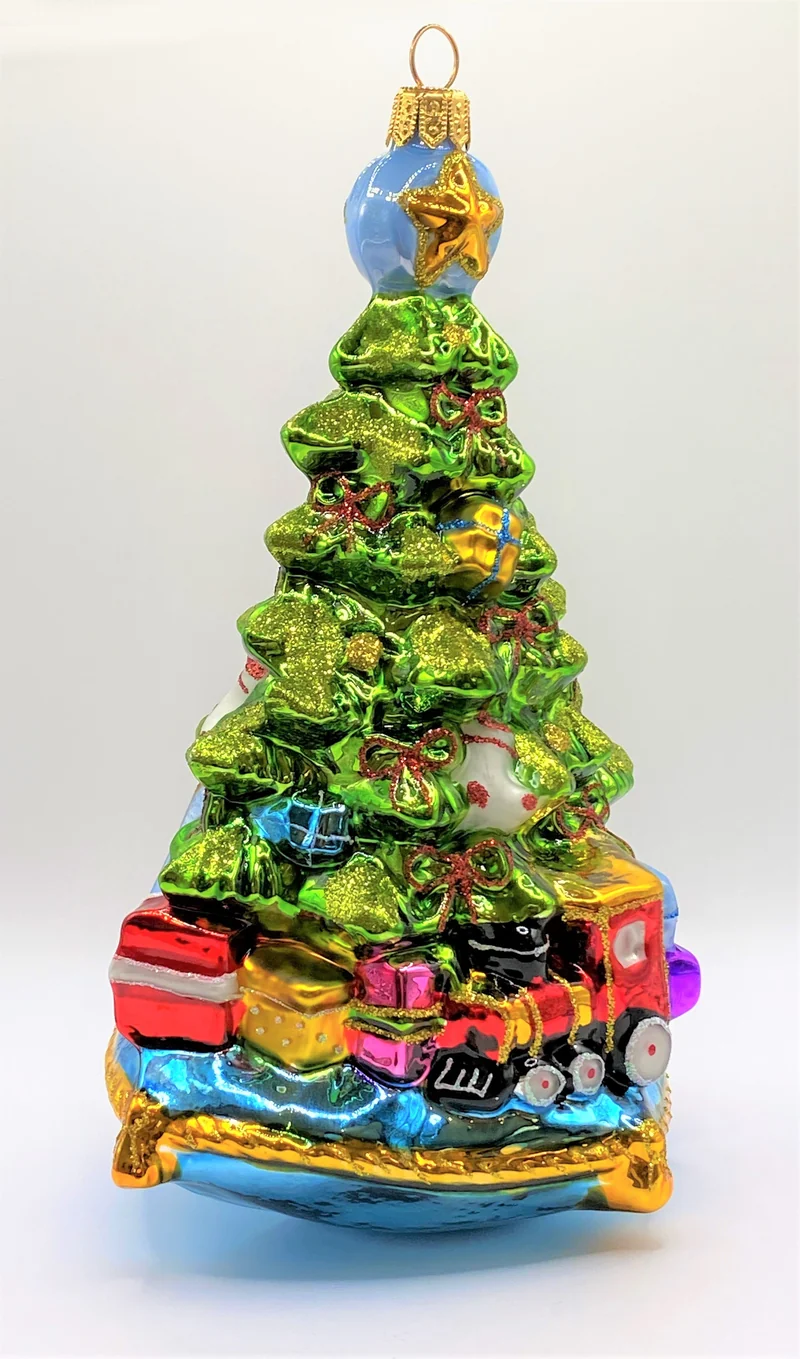 Christbaum mit Teddybär, Lokomotive und Segelboot auf blauem Kissen