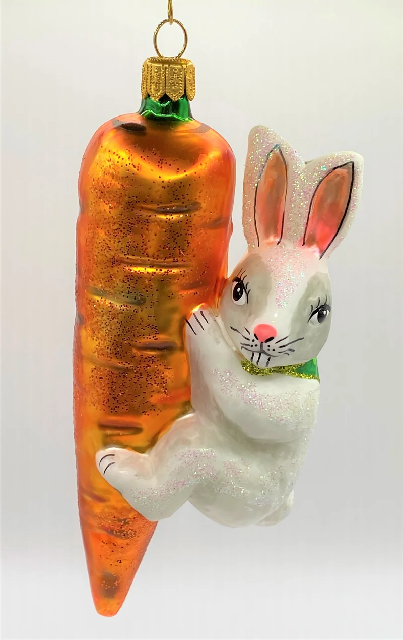 Weisser Osterhase klettert an der Karotte