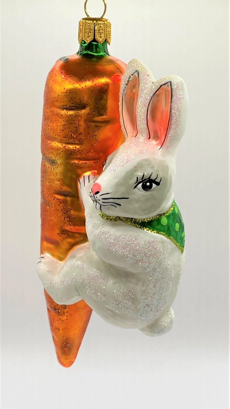 Weisser Osterhase klettert an der Karotte
