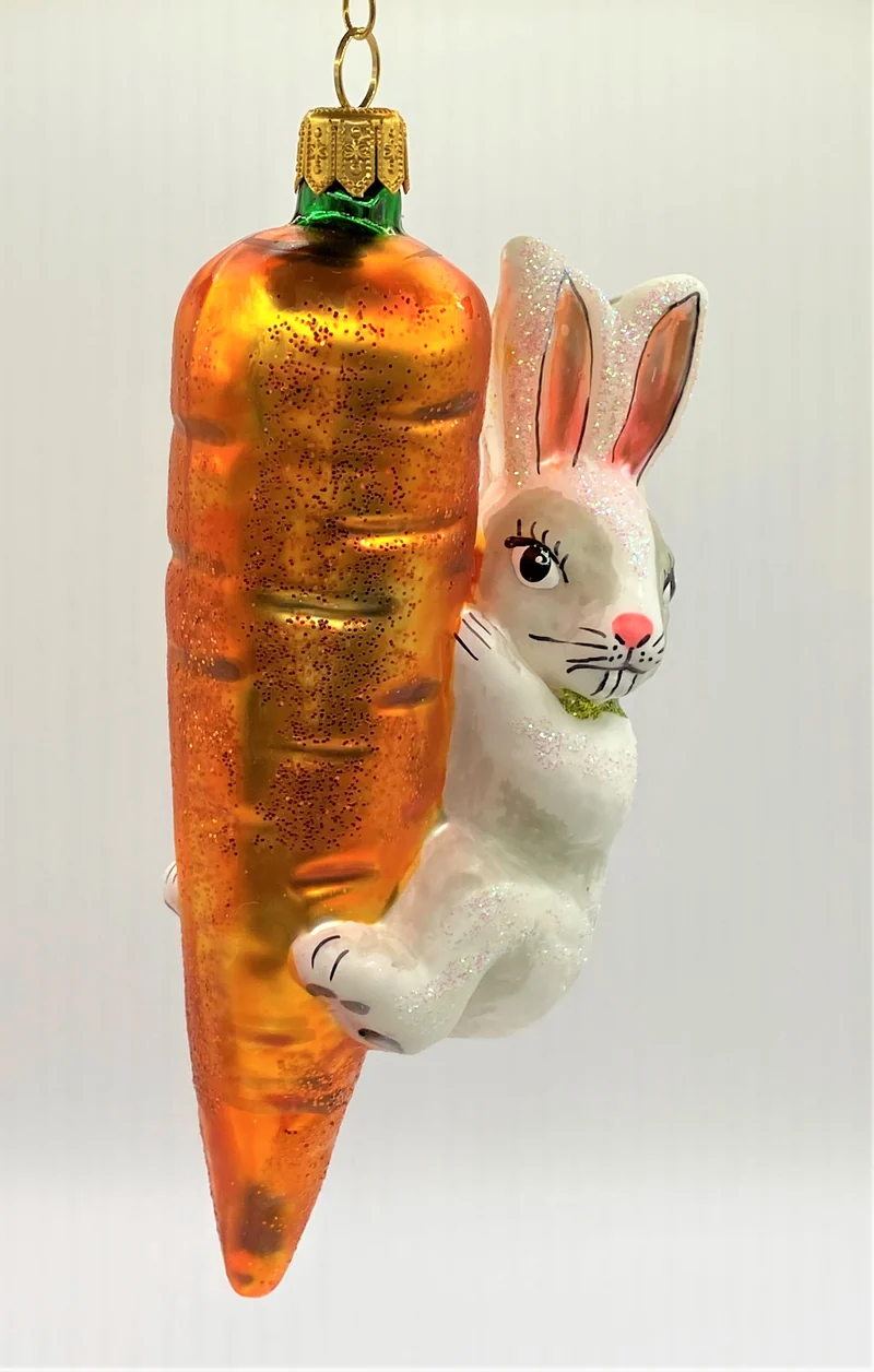 Weisser Osterhase klettert an der Karotte